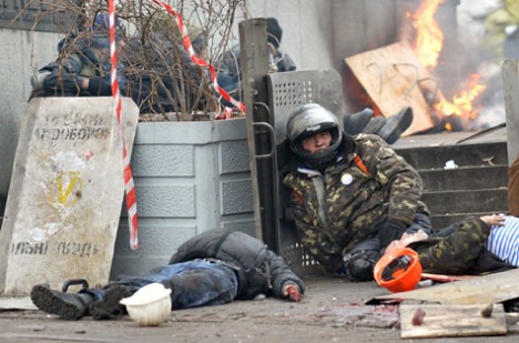 Một BT viên ngồi cạnh thi thể của hai “đồng đội” chết vì đạn bắn tỉa hôm 20/2 (Getty Images)